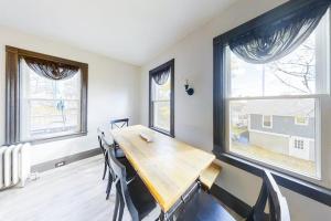 a dining room with a wooden table and two windows at Newly Renovated Haven w/ Deck, Walk to Shops, Dining & Marina, Pet friendly in Boothbay Harbor