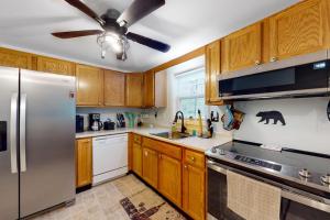 a kitchen with wooden cabinets and a stainless steel refrigerator at Serene home with a deck, grill, firepit, board games, washer/dryer, & mtn views in East Lamoine