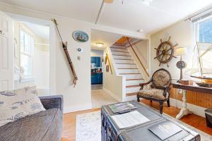 a living room with a couch and a table and stairs at Historic Boothbay Harbor cottage with antique decor, washer/dryer & deck in Boothbay Harbor