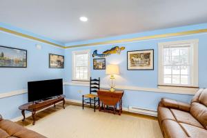 a living room with a couch and a flat screen tv at Colorful duplex home with a large yard, deck, WiFi, & ideal Midcoast location in Boothbay