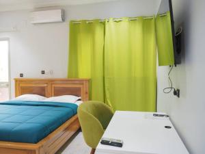 a bedroom with a bed and a green curtain at OABY'S Hôtel in Bobo-Dioulasso +70 photos