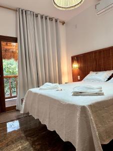 a bedroom with a large white bed with a window at Prainha do Jet in Tianguá +28 photos