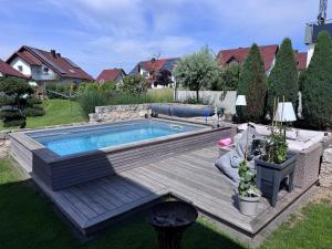 a swimming pool in a yard with a wooden deck at Secret Garden Spa House - Pool & Sauna in Großenlüder