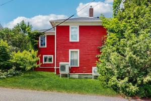 a red house with two chairs in front of it at Dog-Friendly House with WiFi and Deck - Near the Water, Eateries, and Shopping in Bar Harbor