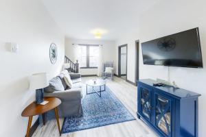 a living room with a couch and a flat screen tv at Newly Renovated Haven w/ Deck, Walk to Shops, Dining & Marina, Pet friendly in Boothbay Harbor