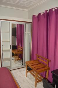 a room with purple curtains and a wooden bench at OABY'S Hôtel in Bobo-Dioulasso
