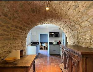 a kitchen with an archway in a stone wall at Maison des lavandes in Apt