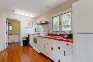 a kitchen with white cabinets and a white refrigerator at Ocean Point Colony Home w/ Sunroom & Sweeping Ocean Views, Dog-friendly in East Boothbay +21 photos