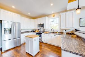 a kitchen with white cabinets and a stainless steel refrigerator at Secluded hilltop home with beautiful Cadillac Mountain view and multiple decks in Bar Harbor
