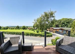 eine Terrasse mit zwei Stühlen und einer Straße in der Unterkunft The Lodge-Static Holiday Lodge in Carnforth