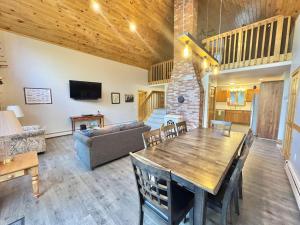 a living room with a wooden table and a couch at Riverfront home w/ deck, amazing views & firepit - near the best of Maine in Stockton Springs