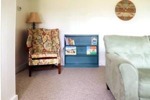 a living room with a chair and a book shelf at Ocean-view cottage near beach with deck, grill, & full kitchen in Bristol