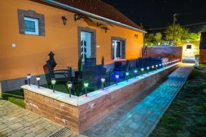 a brick retaining wall with lights in front of a house at Déjá-Vu Apartmanház in Szigetvár