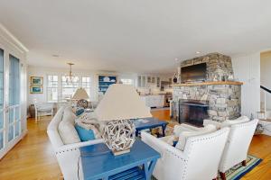a living room with white furniture and a stone fireplace at Oceanfront home incredible ocean views, deck & location in Boothbay