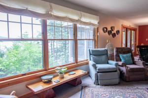 a living room with two chairs and a table and windows at Gorgeous lakefront home w/ dock, canoe, kayaks & lake/forest views in Ellsworth