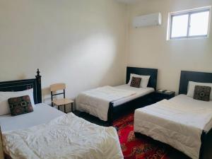 a room with three beds and a window at Yasin Holiday Hotel in Gilgit