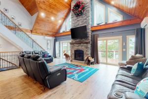 a living room with couches and a stone fireplace at Luxurious waterfront home with deck, firepit, hot tub, fireplace, & pool table in Boothbay