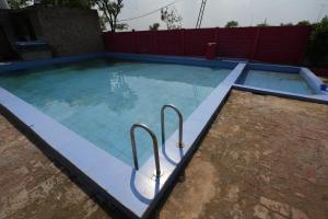 a large swimming pool with two metal rails in it at Rupani Dhani Farmhouse by Belmore in Mandkaula +21 photos