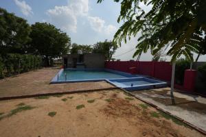 an empty swimming pool in a yard next to a fence at Rupani Dhani Farmhouse by Belmore in Mandkaula