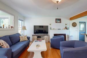 a living room with blue couches and a tv at Charming Cottage with Cozy Comfort and Easy Access to Outdoor Adventures in North Lamoine