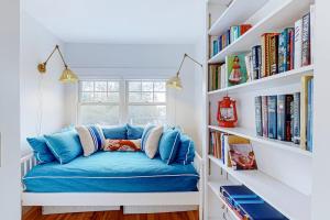 a blue couch sitting in a room with bookshelves at Enchanting Oceanfront Cottage with Breathtaking Views and Modern Comforts in East Boothbay