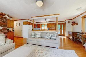 a living room with a couch and a kitchen at Secluded waterfront home with private dock, outdoor dining, firepit, WiFi & W/D in Orland