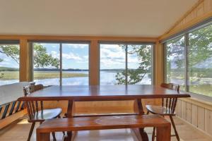 a table and chairs in a room with windows at Luxe Bayfront Cabin w/ Stunning Views & Shared Dock- Ideal for Hunting & Fishing in Bowdoinham