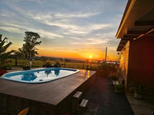 a hot tub on a patio with the sunset in the background at Rancho Cata Vento in Santa Clara dʼOeste