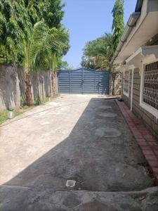a driveway of a house with a gate and palm trees at Mobi house Malindi in Malindi +5 photos