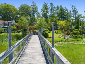 a wooden bridge over a park with trees at Mabel's Maine Studio on the River in Edgecomb