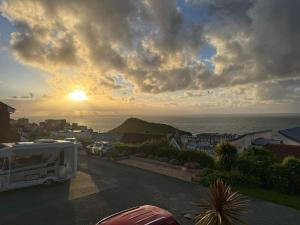 a camper van parked on a street with the sunset at Ocean View, 3 bed 2 bath, Dog Friendly, Private parking, Beach 9 min walk, sleeps 6 in Ilfracombe