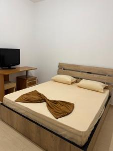 a bed with a brown blanket on it with a television at Garden House - Hamallaj in Hamallë