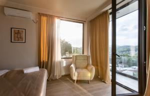 a bedroom with a chair and a large window at AUTOGRAPH Kutaisi in Kutaisi