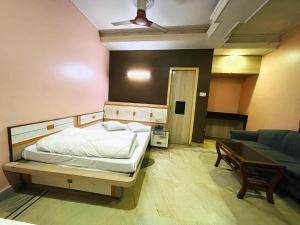 a bedroom with a bed and a table and a couch at Hotel Haven in Agartala