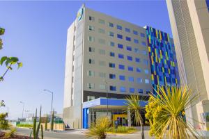a large building with palm trees in front of it at Tru By Hilton Puebla Angelopolis in Puebla