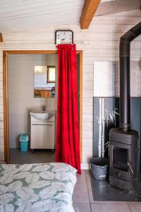 a bedroom with a red curtain and a stove at chalet 2 personnes in Mialanes