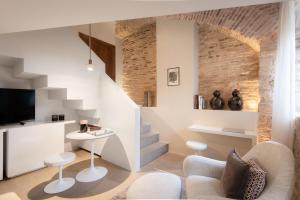 a living room with white furniture and a staircase at Nun Assisi Relais & Spa Museum in Assisi