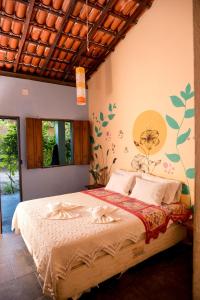 a bedroom with a bed with a flower mural on the wall at Pousada Templo Aláfia in Vera Cruz de Itaparica +29 photos