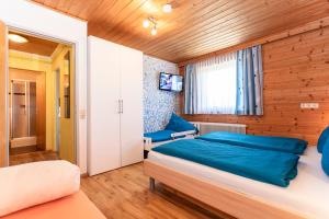 a bedroom with a bed with blue sheets and a window at Bergbauernhof Familienparadies Oberhasenberghof in Taxenbach +76 photos
