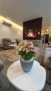 a vase with flowers on a table in a room with a fireplace at فلل و شقق سحاب أبها in Abha