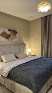 a bedroom with a large bed with a blue blanket at غرفة وصالة دخول ذكي in Al Fayşalīyah