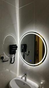 a mirror in a bathroom with a sink and a phone at غرفة وصالة دخول ذكي in Al Fayşalīyah +7 photos