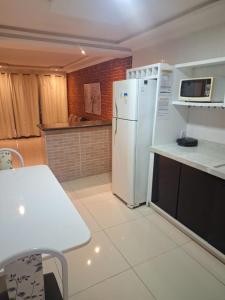 a kitchen with a white refrigerator and a table at espaço inteiro no bairro mais tranquilo de gravatá in Gravatá