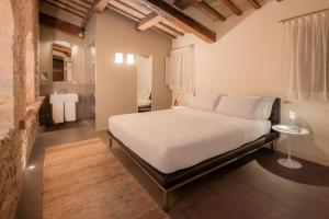 a bedroom with a large white bed and a bathroom at Nun Assisi Relais & Spa Museum in Assisi +42 photos