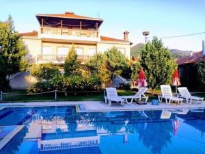 a group of chairs and a swimming pool with a house at Prespa Resort & Spa in Platy