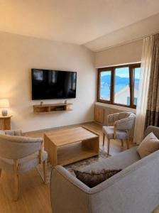 a living room with a tv and a couch and chairs at 101 Apartments in Igalo