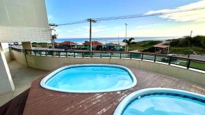 a hot tub on a deck with a view of the ocean at Studios Praia Grande - VISTA MAR in Arraial do Cabo