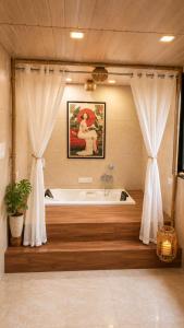 a bathroom with a tub and a painting of a woman at Jacuzzi Room in a shared Villa with Swimming pool in Thane