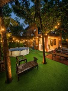 a backyard with a table and benches and lights at Jacuzzi Room in a shared Villa with Swimming pool in Thane
