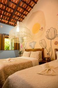 a bedroom with two beds and a mural on the wall at Pousada Templo Aláfia in Vera Cruz de Itaparica